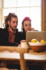 Giovane coppia in cerca di laptop mentre seduto al tavolo a casa — Foto stock