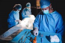 Chirurgien prenant des ciseaux du plateau pendant l'opération — Photo de stock