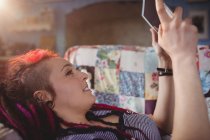 Молода хіпстерка використовує цифровий планшет, розслабляючись на дивані вдома — стокове фото