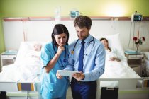 Врач и медсестра с помощью цифрового планшета в палате больницы — стоковое фото