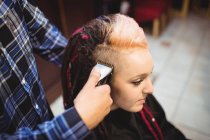 Femme se faire couper les cheveux avec tondeuse dans le salon de coiffure — Photo de stock