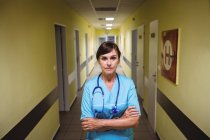Портрет медсестри, що стоїть з обіймами, схрещеними в лікарняному коридорі — стокове фото