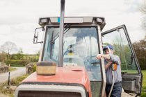 Landarbeiter zeigt beim Stehen mit Traktor auf Feld — Stockfoto