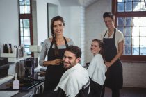 Портрет улыбающихся парикмахеров, работающих с клиентами в парикмахерской — стоковое фото