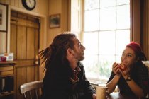 Couple souriant tout en prenant un café à table dans la maison — Photo de stock