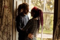 Молода пара обіймається вікном вдома — стокове фото
