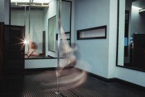 Dançarina de pólo praticando pole dance no estúdio de fitness — Fotografia de Stock
