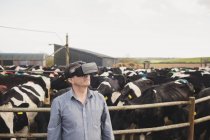 Farmer using virtual reality simulator by fence at barn — Stock Photo