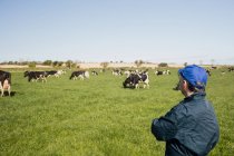 Працівник ферми стоїть на трав'янистому полі на тлі чистого неба — стокове фото