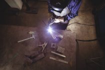 Hochwinkelaufnahme einer Schweißerin, die in der Werkstatt an einem Metallstück arbeitet — Stockfoto