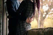 Midsection of young couple embracing by window at home — Stock Photo