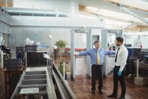 Flughafensicherheitsbeamter mit einem Metalldetektor zur Kontrolle eines Passagiers am Flughafen — Stockfoto