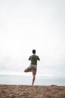Vista posteriore dell'uomo che esegue yoga sulla spiaggia — Foto stock
