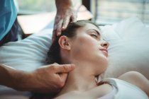 Мужской физиотерапевт делает массаж шеи пациентке в клинике — стоковое фото