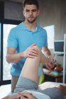 Male physiotherapist giving knee massage to female patient in clinic — Stock Photo