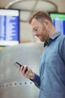 Passager masculin utilisant un téléphone portable dans le terminal de l'aéroport — Photo de stock