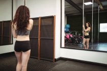 Задний вид танцовщицы с шестом и зеркало в фитнес-студии — стоковое фото