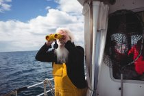 Pescatore che guarda attraverso il binocolo dalla barca — Foto stock