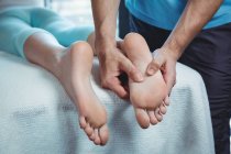 Image recadrée du physiothérapeute masculin qui donne un massage des pieds à une patiente en clinique — Photo de stock