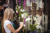 Florista feminina organizando flores em vaso em sua loja de flores — Fotografia de Stock