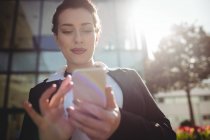 Молода бізнес-леді, використовуючи мобільний телефон в сонячний день — стокове фото
