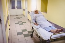 Senior mulher deitada em uma maca no corredor do hospital — Fotografia de Stock