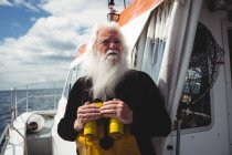 Fischer hält Fernglas in der Hand und schaut vom Boot weg — Stockfoto