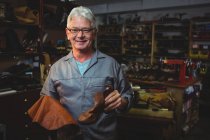 Cordonnier mature tenant une botte et un morceau de matériau dans l'atelier — Photo de stock