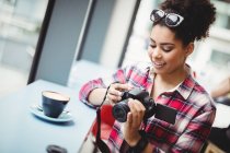 Sorridente giovane donna che tiene la fotocamera mentre in piedi al ristorante — Foto stock