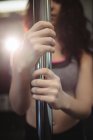 Cropped image of pole dancer holding pole in fitness studio — Stock Photo