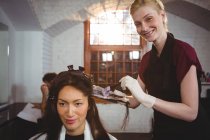 Портрет усміхнене жіночий перукар фарбування волосся її клієнта в салон — стокове фото