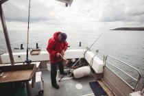 Рибалка середнього віку тримає рибу на човні — стокове фото