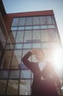Vista basso angolo di donna schermatura occhi contro edificio per uffici — Foto stock