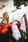 Fleuriste féminine organisant des fleurs dans la boutique de fleurs — Photo de stock