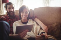 Пара, використовуючи цифровий планшетний у вітальні на дому — стокове фото