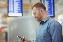 Чоловік пасажир використовує мобільний телефон в терміналі аеропорту — стокове фото