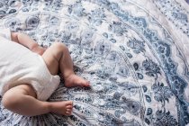Abgeschnittenes Bild eines Babys, das zu Hause im Schlafzimmer auf dem Bett liegt — Stockfoto