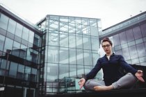 Longitud completa de empresaria concentrada haciendo yoga contra la construcción - foto de stock