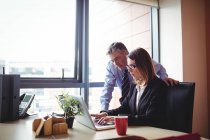 Geschäftsmann diskutiert mit Geschäftsfrau über Laptop im Büro — Stockfoto