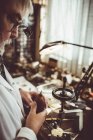Uhrmacher hält ein Staubgebläse in der Hand, während er die Uhrenfräsmaschine in der Werkstatt benutzt — Stockfoto