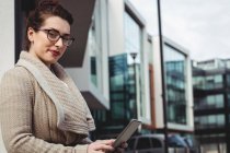 Portrait de femme tenant une tablette numérique contre un bâtiment moderne — Photo de stock