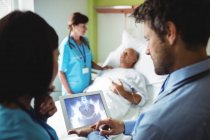 Мужчина врач и медсестра смотрят на цифровой планшет в больнице — стоковое фото