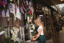 Fiorista femminile che organizza fiori in scatola di legno presso il suo negozio di fiori — Foto stock