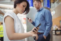 Empresários usando telefones celulares no terminal do aeroporto — Fotografia de Stock