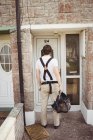 Back view of Carpenter standing with tool bag near house door — Stock Photo