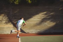 Мужчина играет в теннис на спортивном корте днем — стоковое фото