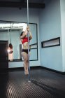 Bela dançarina Pólo praticando pole dance no estúdio de fitness — Fotografia de Stock