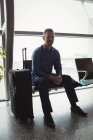 Geschäftsmann sitzt mit Gepäck im Wartebereich im Flughafenterminal — Stockfoto
