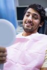 Пацієнт перевіряє свою посмішку після стоматолога — стокове фото
