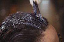 Обрезанное изображение парикмахера окрашивающего волосы клиента в салоне — стоковое фото